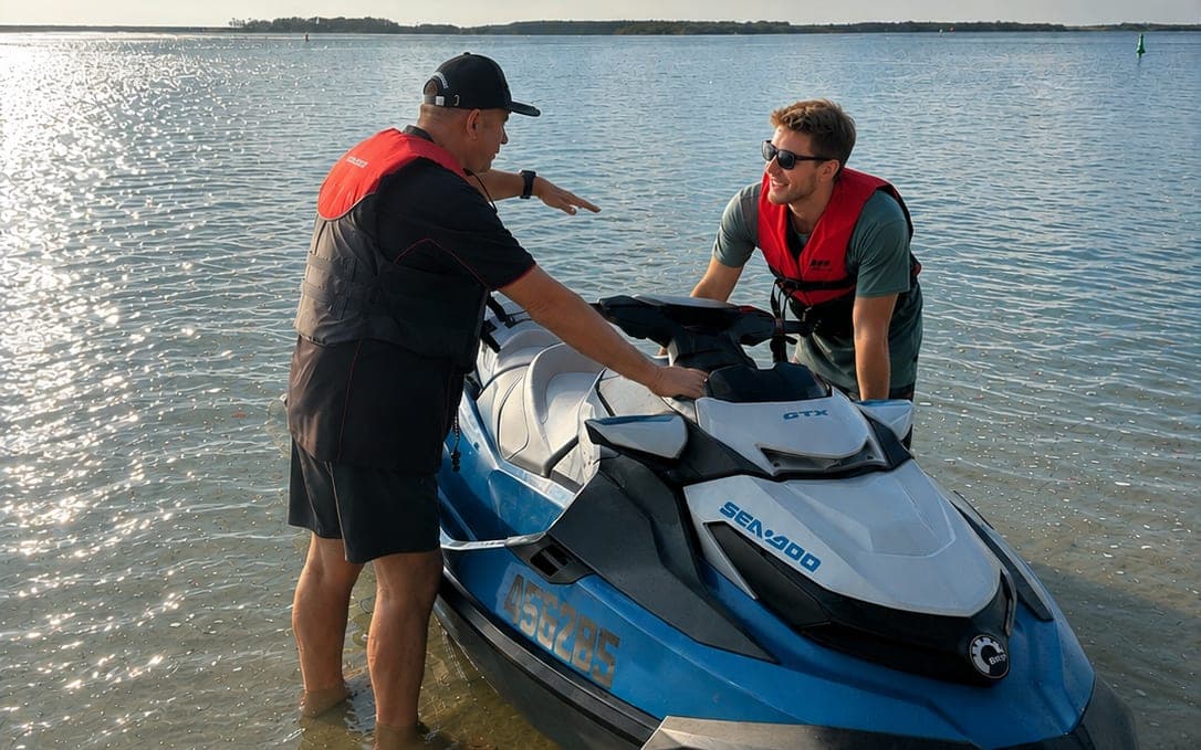 An ABC Boating instructor briefing a student beside a Sea-Doo jet ski in shallow water during a jet ski licence course