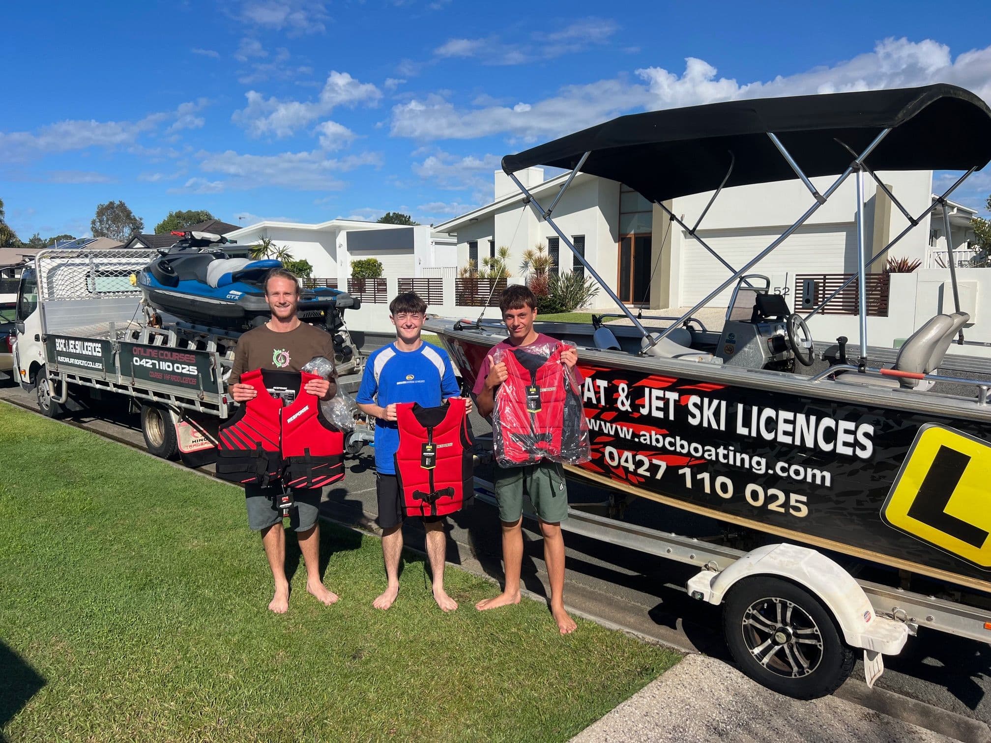 Students with their new lifejackets beside the ABC Boating boat and jet ski